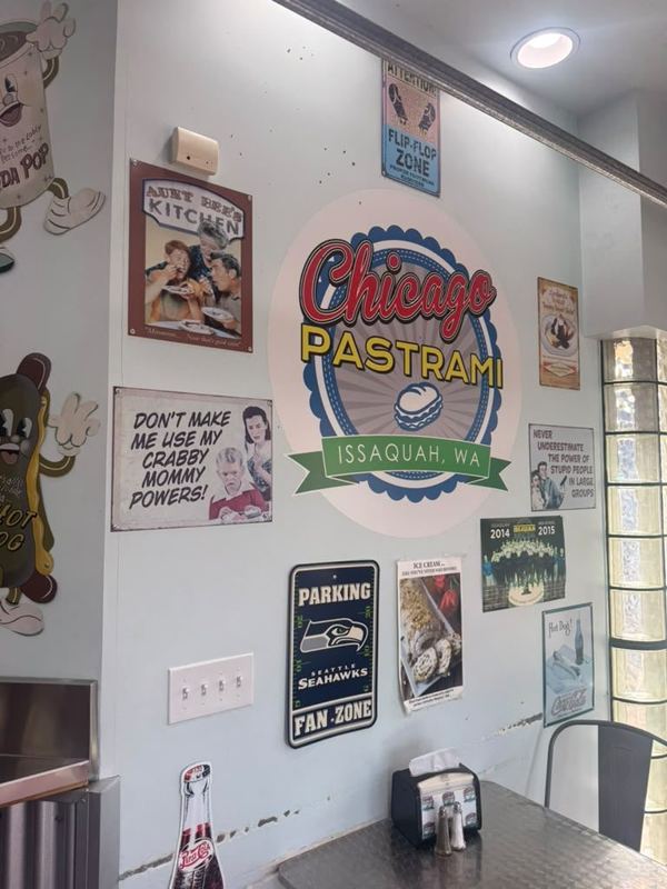Dining area wall with the Chicago Pastrami logo, vintage tin signs and a Seahawks Fan Zone sign